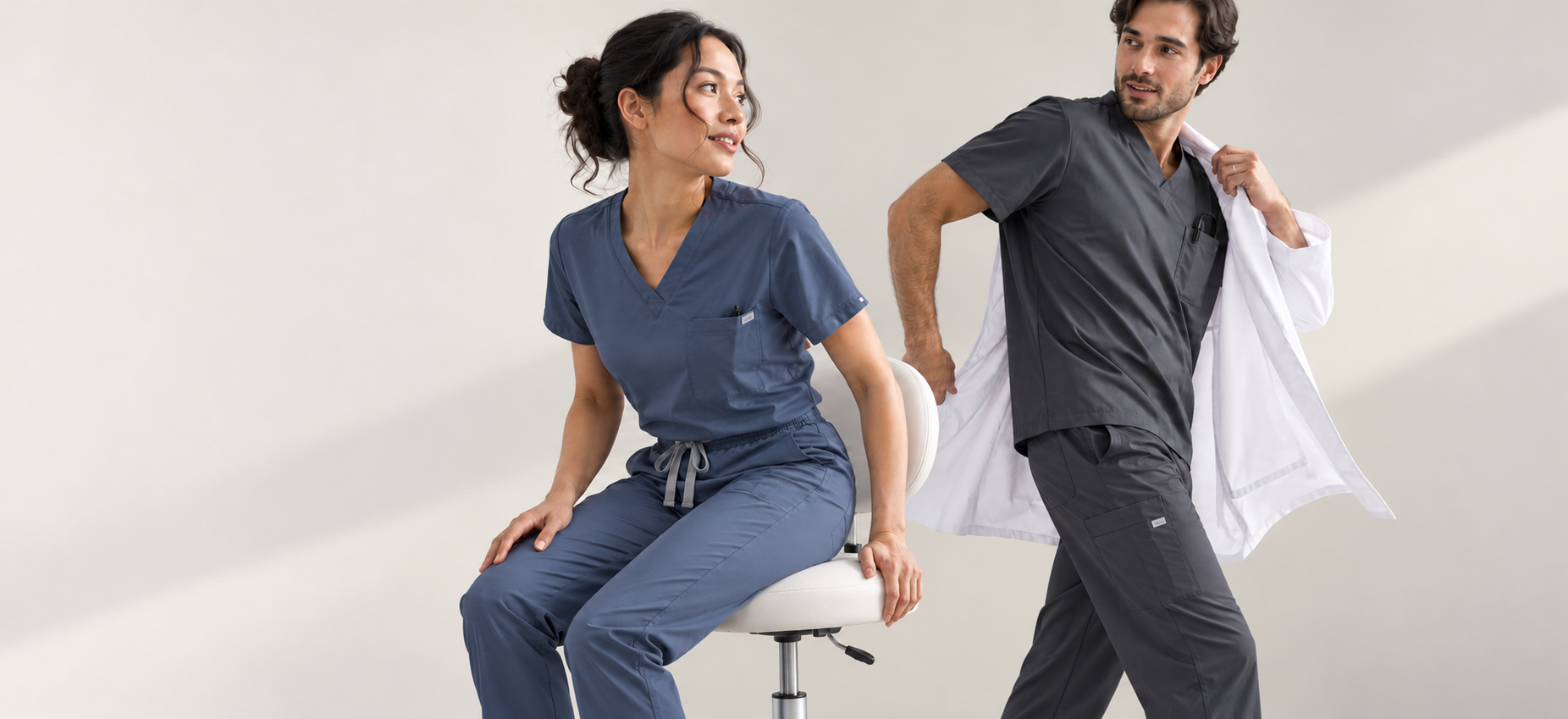 Two healthcare professionals in slate and charcoal scrubs sharing a natural moment
