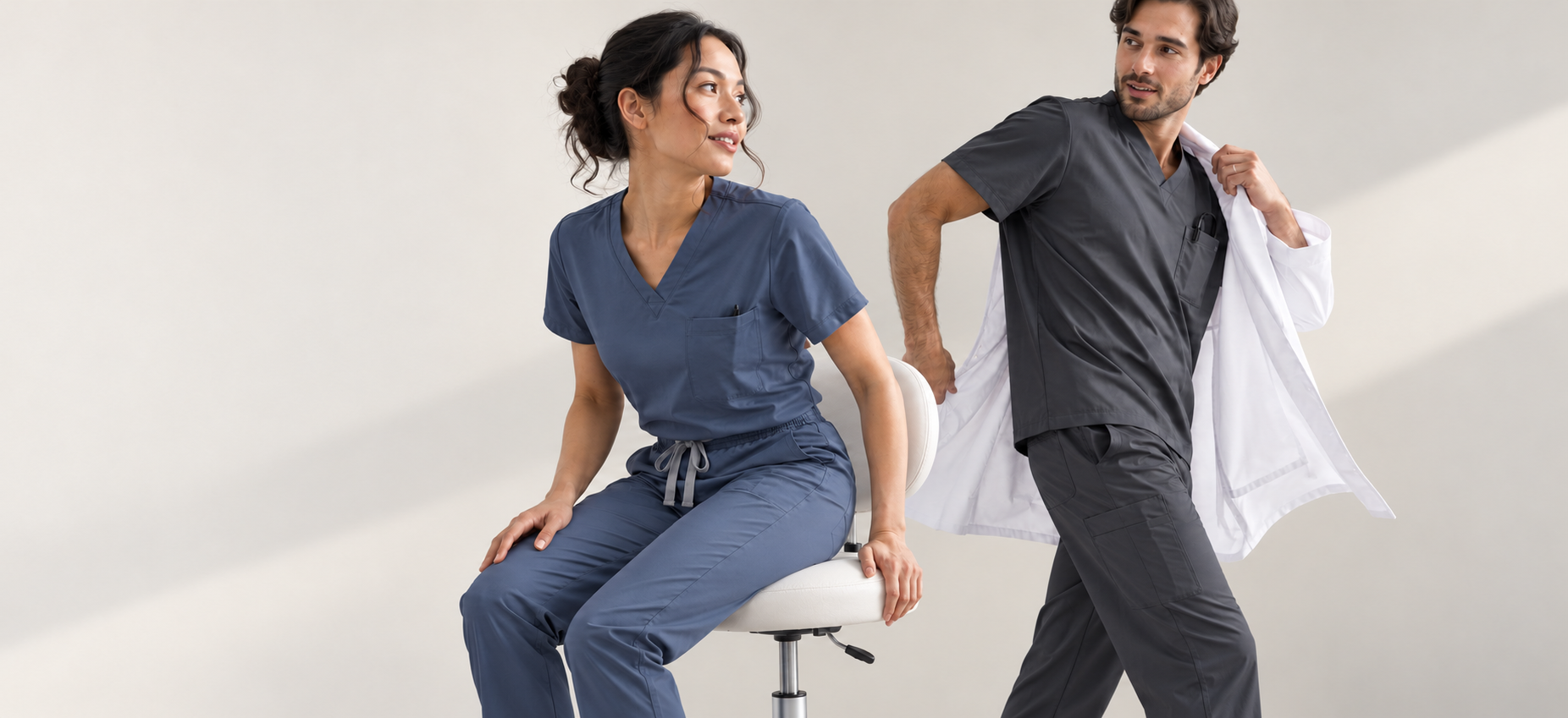 Two healthcare professionals in slate and charcoal scrubs sharing a natural moment